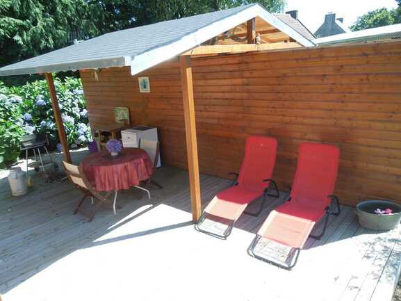 une terrasse en bois privative semi-couverte équipée  d'un salon de jardin et barbecue